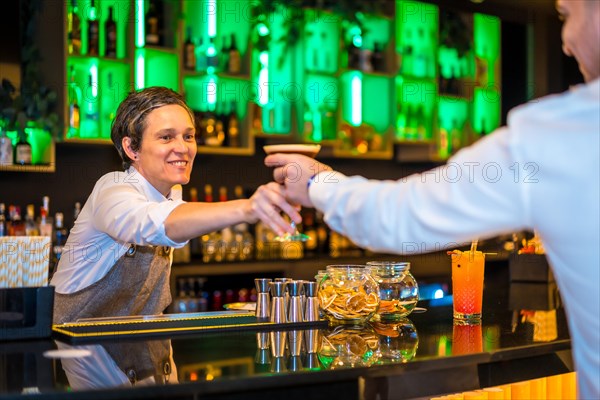 Bartender serving a martini cocktail in a luxury bar to a man