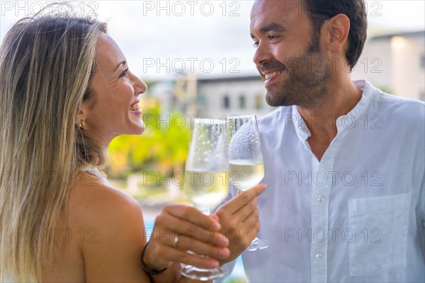 Romantic couple smiling and celebrating honeymoon with champagne in an hotel terrace