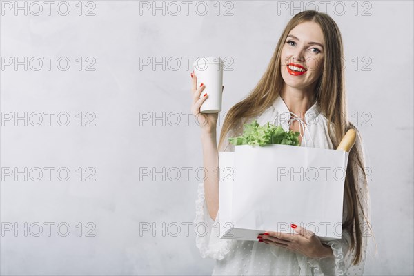 Beautiful young woman holding groceries bag