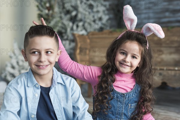 Girl bunny ears making horns with fingers boy