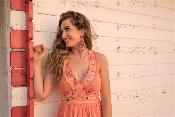 Portrait with copy space of a smiling distracted beauty woman leaning on a beach house