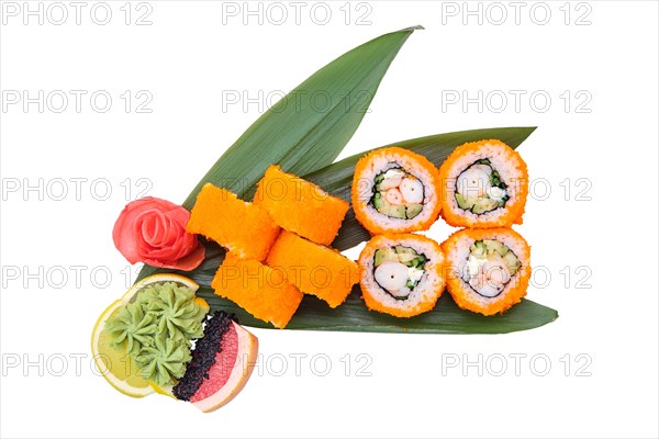 Overhead view of shrimp roll with avocado and caviar on top served on bamboo leaves