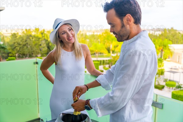 Relaxed man and woman opening a champagne bottle in an hotel