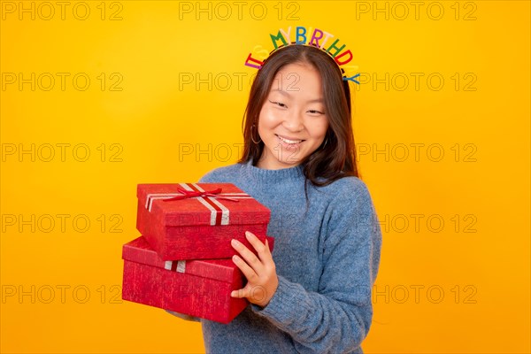 Studio photo with yellow background of a chinese woman receiving gifts for her birthday