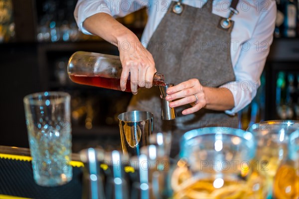 Close-up of an unrecognizable female bartender preparing a luxury cocktail in a restaurant at night