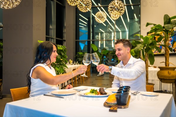 Couple toasting with white wine during a dinner in a luxury restaurant