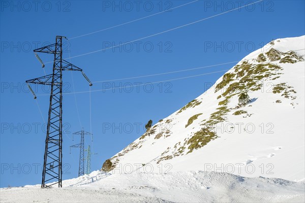 High voltage cable towers in the winter landscape with snow in the snowy mountains of the Pyrenees of Andorra