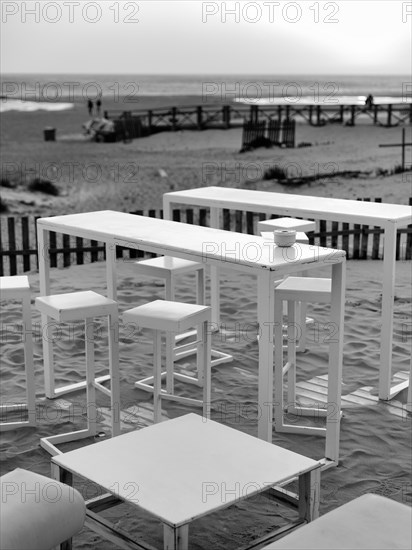 Empty tables and chairs in the sand