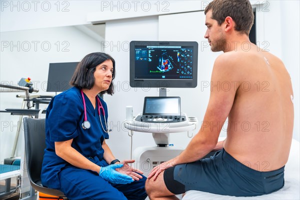 Rear view of a male patient and female doctor cardiologist looking at the results of an echocardiogram in the hospital