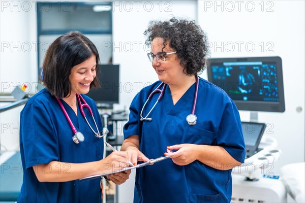 Smiling and cheerful team of cardiologists doing paperwork standing on the hospital