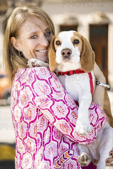 Female hugging friendly beagle dog enjoying happy moments while both look at camera