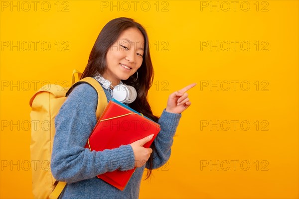 Studio photo with yellow background of a chinese student with folders