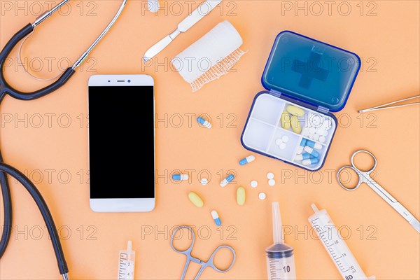 Medical pill box stethoscope mobile phone medical equipment s orange background