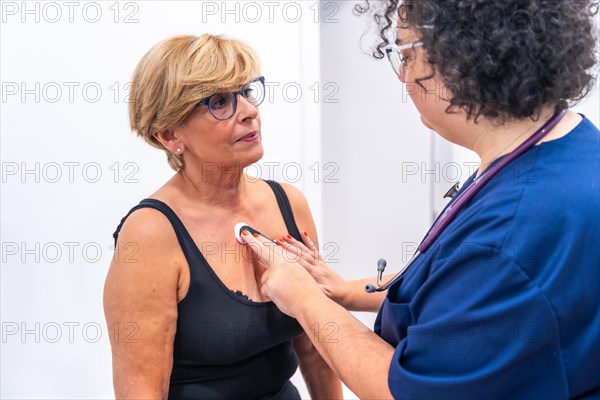 Female doctor putting woman with heart problems undergoing ECG Holter monitor test with innovative device