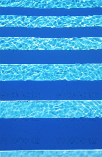 Water surface with light reflections and pool stairs in a swimming pool