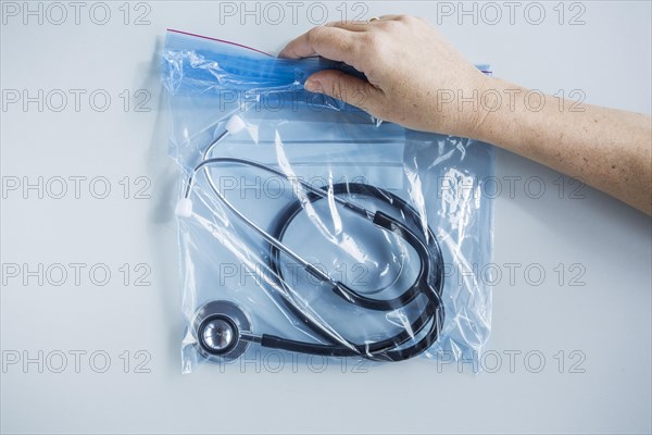Human hand holding zip lock plastic bag with stethoscope