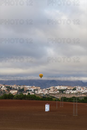 Mountain landscape with the city of Ronda in the background and a hot air balloon in the sky
