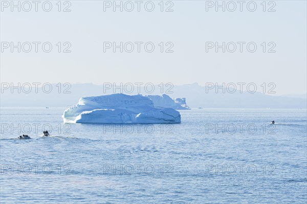 Evening atmosphere in Disko Bay near Ilulissat. Small boats sail near two icebergs. Ilulissat