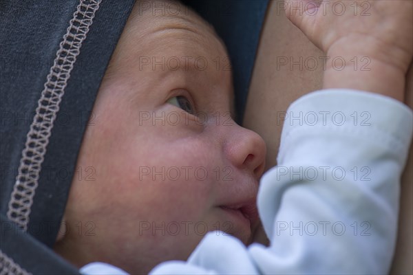 Premature baby in sling with mother