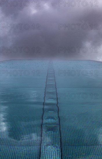 Rippled water surface during rain in swimming pool with dramatic cloudy sky