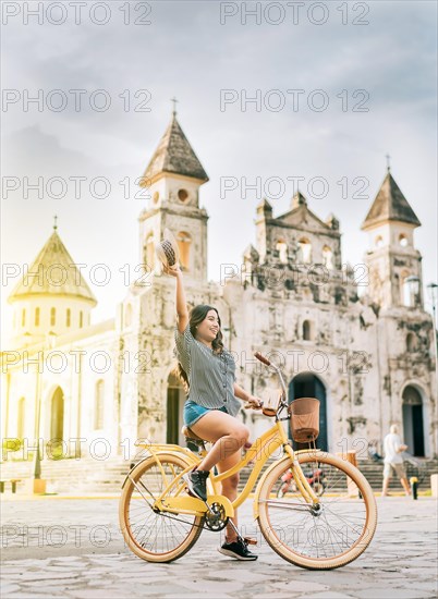 Happy young woman in hat riding a bicycle on the street. Granada