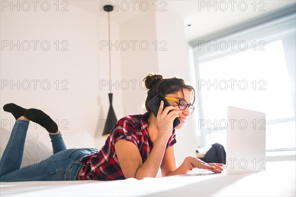 Side view of a young woman talking to the mobile while working from a hotel room