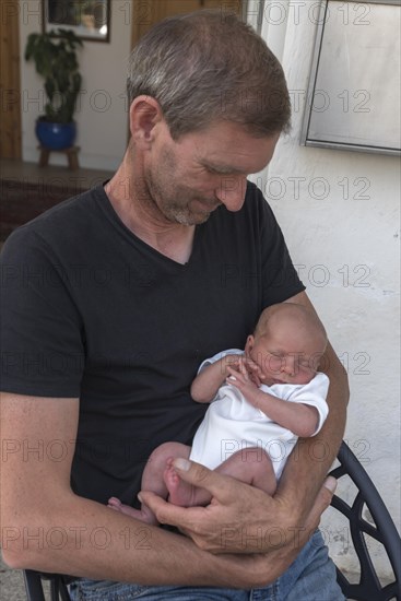 Young grandpa with his newborn grandson in his arms