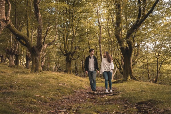 Frontal view of lovers holding hands and walking in the forest