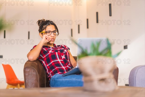 Portrait of a young pensive female freelance using laptop working from home