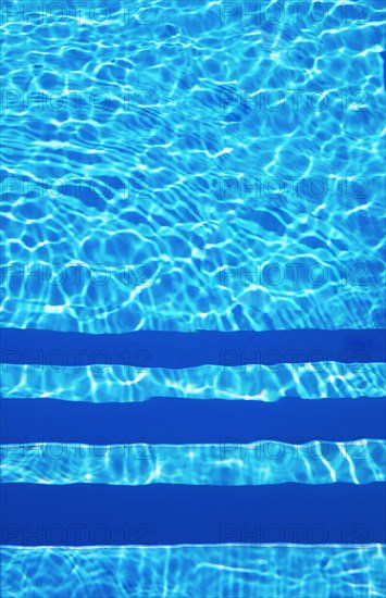 Water surface with light reflections and pool stairs in a swimming pool