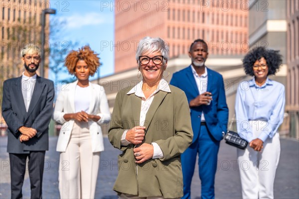 Frontal portrait of a mature businesswoman stand next to his work team outdoors