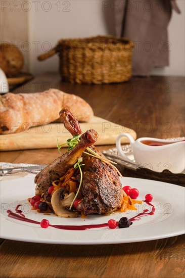 Plate with baked partridge thigh with fried mushrooms and cranberry sauce