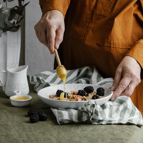 Close up hand pouring honey cereals