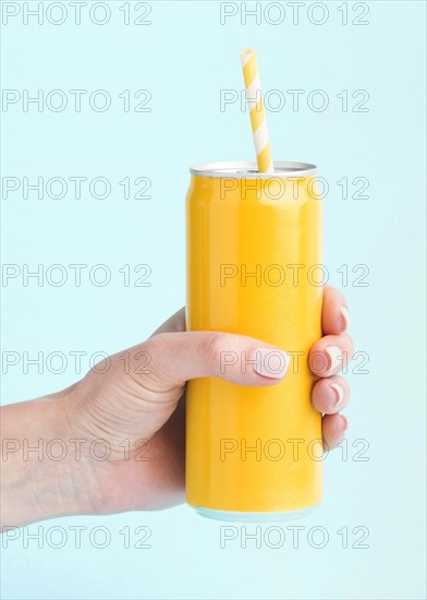 Front view hand holding soft drink can with straw