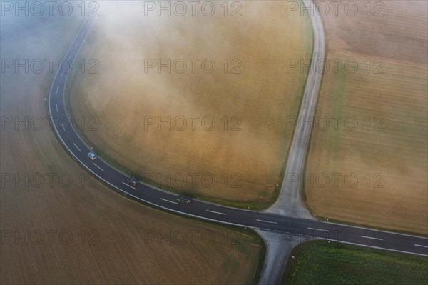 Drone view of a rural landscape shrouded in dense morning fog with a road junction near Prambachkirchen