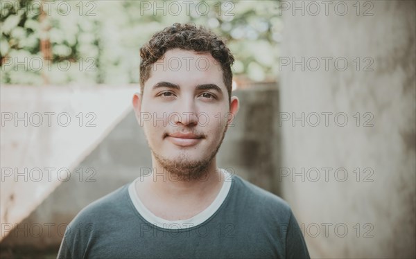 Portrait of cheerful young latin guy smiling at camera outdoors. Portrait of Latin American man looking and smiling at the camera