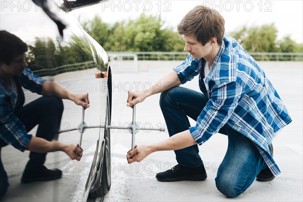 Full shot man changing tire