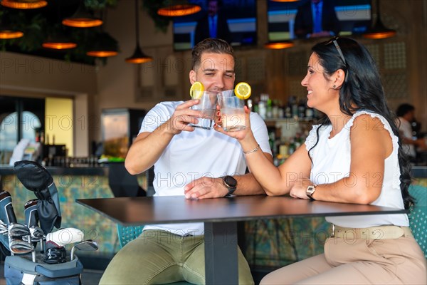 Couple toasting with cocktails on the restaurant of a golf club