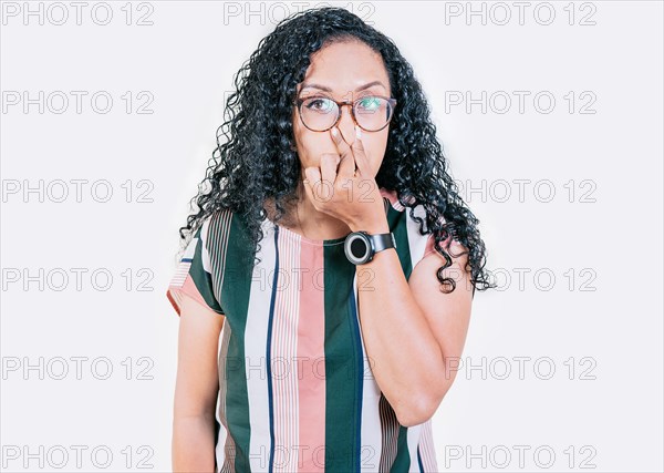 Displeased afro girl holding her nose isolated. Disgusted young afro woman covering nose. Woman in glasses covering nose from a bad smell isolated
