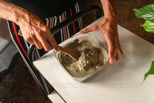 Masseuse preparing mixing clay and water for anti inflammatory massage in spa center