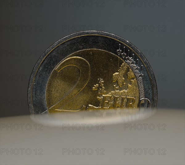 A 2-euro coin as a macro shot in the slot of a piggy bank
