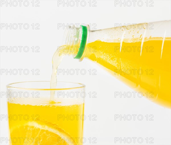 Front view orange juice being poured glass from bottle