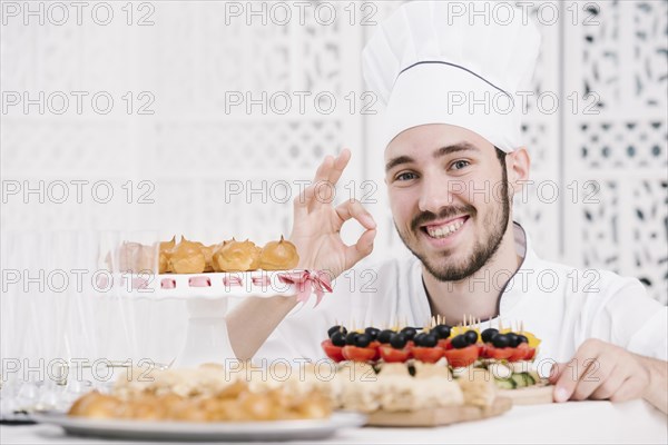 Happy chef presenting food table