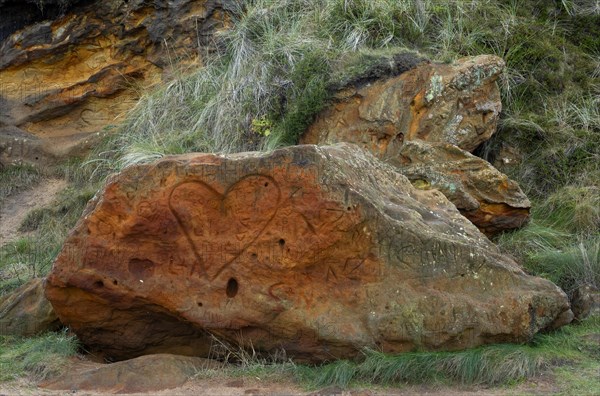 Reddish rock of limonite disfigured with a heart and initials