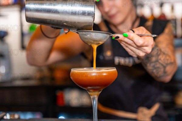 Close-up of a bartender pouring a mixed coffee cocktail into a glass