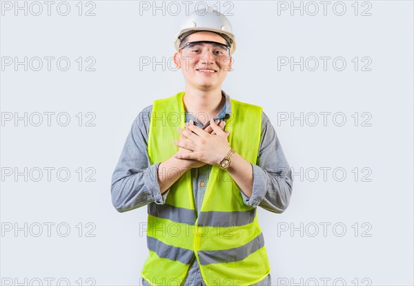 Portrait of young engineer with grateful gesture. Handsome grateful engineer with hands on chest isolated