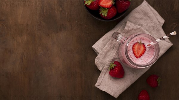 Flat lay strawberry milkshake with straw copy space