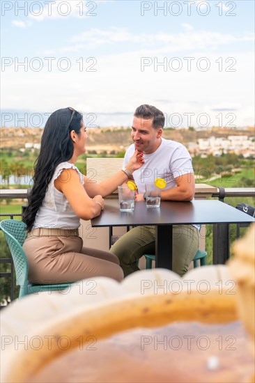 Vertical photo of a romantic couple enjoying a cocktail on a luxury terrace of a golf court