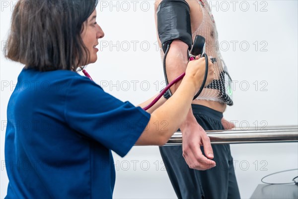 Vertical photo of a doctor measuring blood pressure to a man during a stress test