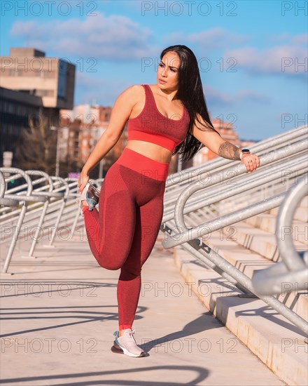 Frontal view of a strong woman stretching legs in an outdoors park